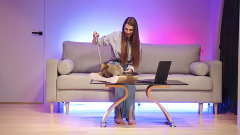 mujer jugando con gatos en un sofá