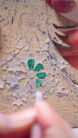 close-up of hands painting intricate floral design on textured wooden surface, showcasing artistic craftsmanship and vibrant colors in creative process