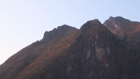 panning-shot-of-mountain-peaks-at-sunset-in-the-mountain-town-of-Nong-Khiaw-in-Laos,-Southeast-Asia