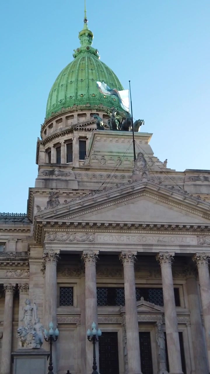 Toma vertical en ángulo bajo con panorámica ascendente del Palacio del Congreso Nacional, Cúpula Verde, Bandera de Argentina, Buenos Aires.