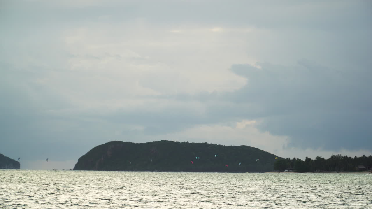 People kitesurfing in the distance in a beach of Koh Phangan, Thailand