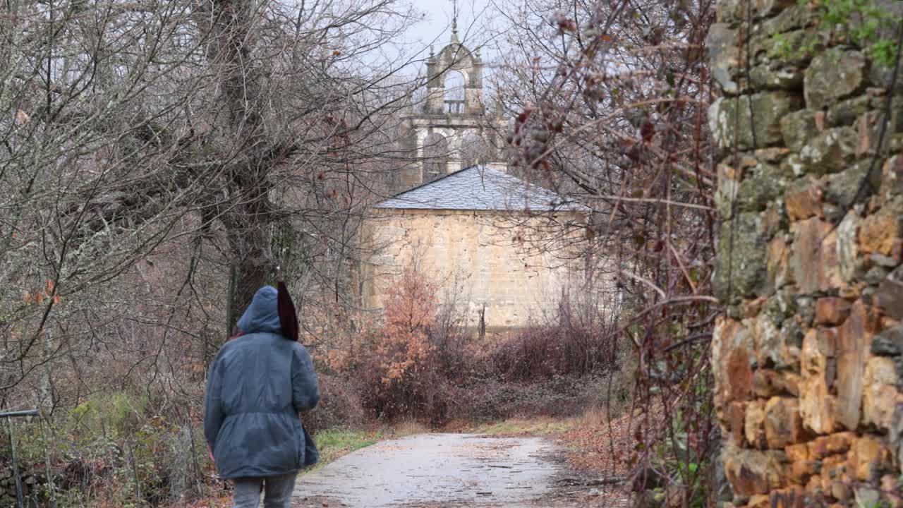 joven caminando hacia una iglesia rural