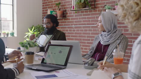 young-indian-businessman-using-tablet-computer-sharing-creative-ideas-presenting-project-showing-colleagues-in-office-meeting-diverse-team-working-together-brainstorming-planning-strategy