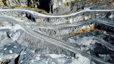 mining drone flying left over deep opencast mine with cliffs and trails trough mine