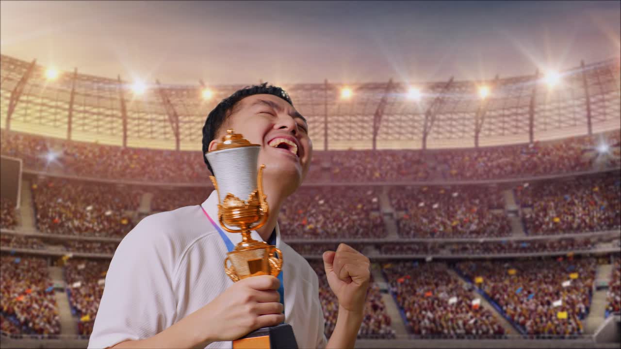 금메달을  아시아인 남자가 금메달을 바라보며 경기장에서 첫 우승을 축하하고 있다.