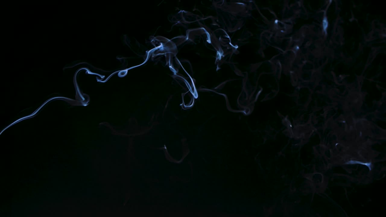색 연기가 서서히 흑색 배경에 대해 나선형으로 위로 올라갑니다. 가까이 가십시오. 느린 동작