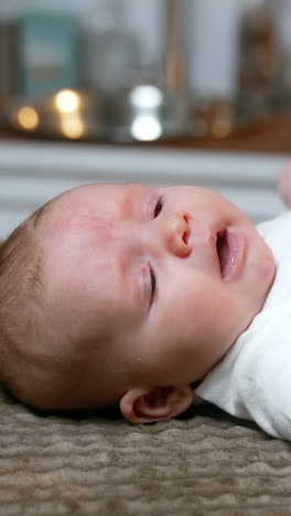 lovely caucasian newborn lies on its back yawning. cute tiny baby boy sneezes adorably. side view close up. vertical video
