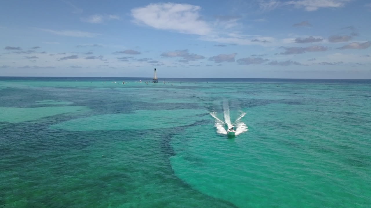 Drone footage of boat leaving Alligator Lighthouse in Atlantic Ocean off coast of Islamorada, Florida Keys in tropical blue water. Shot on Mavic Pro in 4k