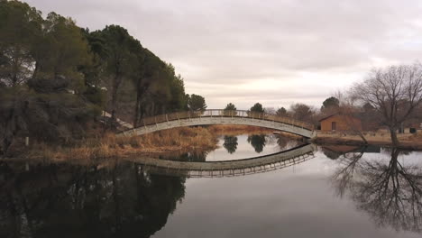 flying over apollo park lake towards a bridge in lancaster, california, fall day