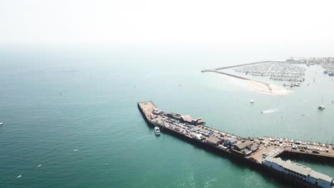 Orbital-of-Santa-Barbara-Pier-with-a-jet-ski-going-under-pier-and-boats-in-the-blue-ocean