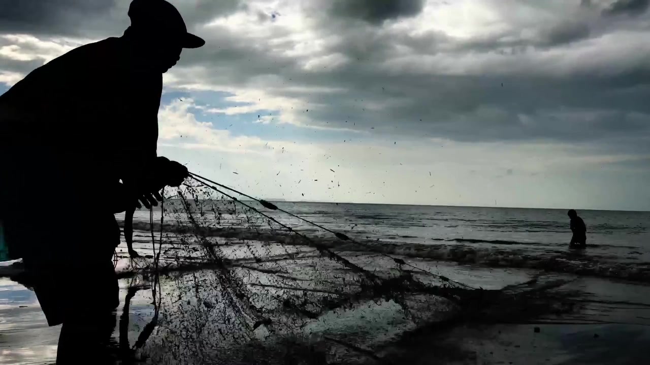 4K filmisk video i høj opløsning af en fisker, der trækker fiskenet op af havet.