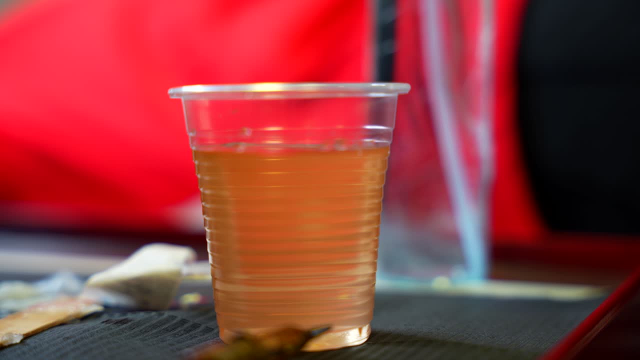 Glass of water on work table as tattoo artist cleans needle with brown ink