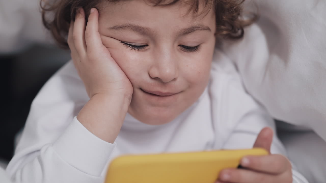 Bambino che guarda il telefono a letto