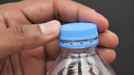mano abriendo una botella de agua de plástico
