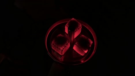 red glowing charcoals on a hookah at night. hot red coals hookah with sparks on shisha on a dark background. smoking hookah or shisha. the pleasure of smoking water pipe.