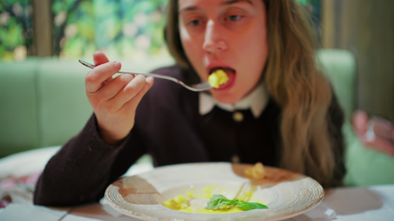 Primo piano di una donna che mangia risotto con verdure in un ristorante.