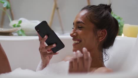 mujer de raza mixta acostada en una bañera en casa