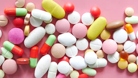 assorted pills and capsules on pink background