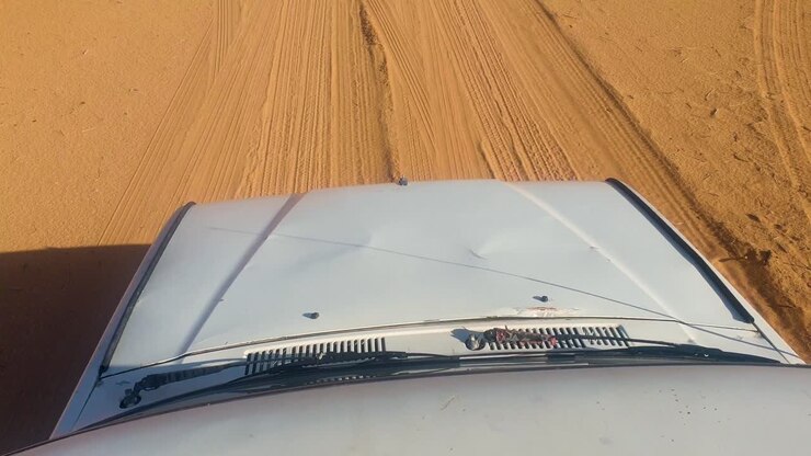 Top down view of bonnet of old four wheel drive truck driving off road through remote, vastness of sandy desert landscape in the wilderness