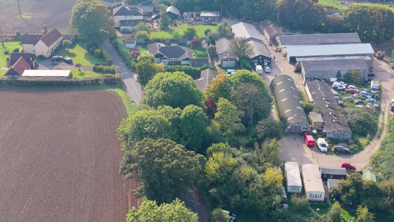 Aerial drone flyover of Nasty, Hertfordshire, UK. Camera tilts at 45 degrees, showing rooftops, houses, trees, and fields, capturing the quirky hamlet name with rural charm and metaphorical potential