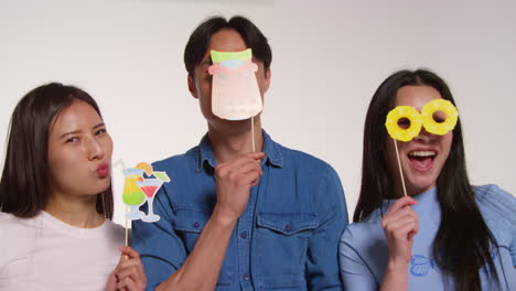 색 스튜디오 배경 앞에 있는 젊은 친구 그룹이 프로페션 3과 함께 사진 부스 스타일의 초상화를 위해 포즈를 취하고 있습니다.