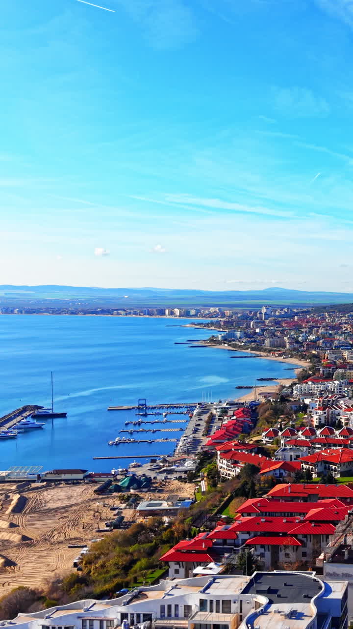 Sortehavskysten, sandstrand, marina med yachter og tæt resortarkitektur på bakken. Panoramisk luftfoto af Saint Vlas kystlinje og havn. Vertikal video.