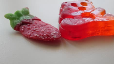 zooming in movement of big red bear and strawberry jellies on a table in studio environment at home