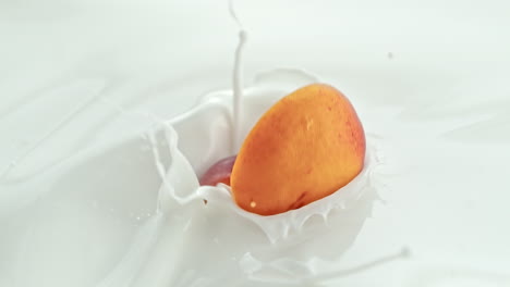 peach halves falling into creamy milk making swirly splashes in macro and slow motion