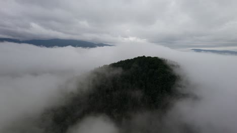 aerial orbit over the mountain summit with the thick condensation vapor down under