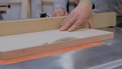 carpenter using circular saw machine, cutting wood plank at workshop - close up