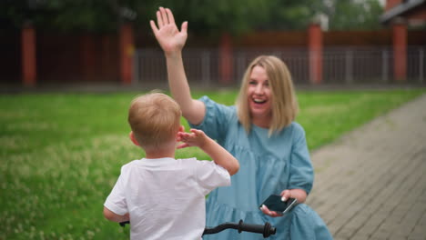 a joyful moment where a mother enthusiastically gives a high five to her children while having a fun time together outdoors