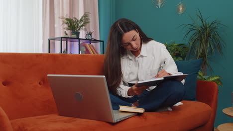 Girl-student-study-at-home-couch-on-laptop-computer-making-conference-video-call-talking-to-webcam