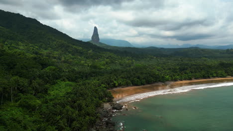 aerial view in front of the praia grande beach with pico cão grande mountain background, in cloudy sao tome