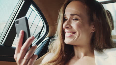 mujer profesional feliz hablando en video chat en el teléfono móvil en el coche de negocios.