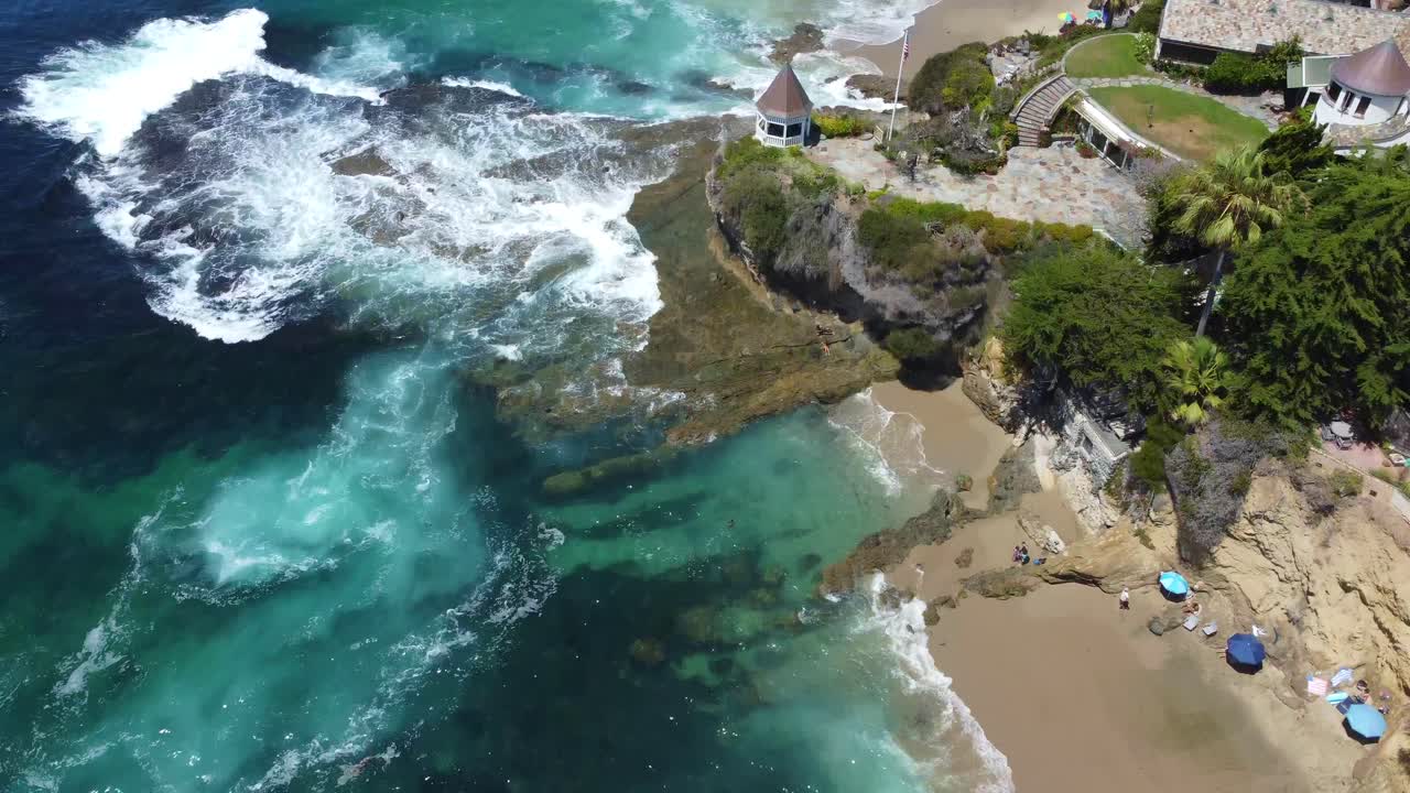 Vista Aérea, Costas Arenosas de Laguna Beach, California, EE. UU., Olas del Océano Bajo Acantilados y Propiedades Frente al Mar, Toma de Dron con Inclinación Ascendente Reveladora