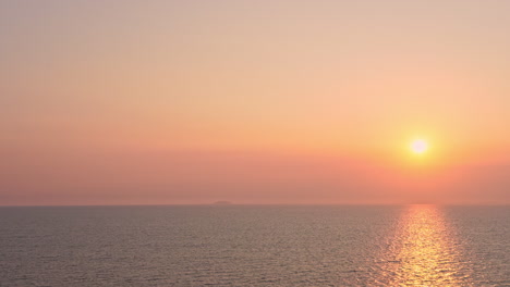 Un-Brillante-Sol-Poniente-Naranja,-Rosa,-Rojo-Y-Amarillo-Se-Cierne-Sobre-Un-Horizonte-Oceánico