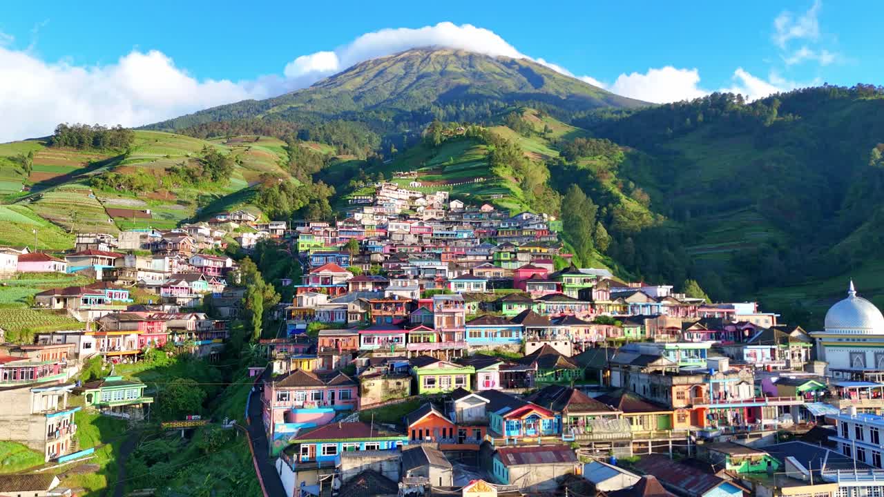 Scenic drone shot of a colorful mountain village known as Nepal van Java. Located on the slopes of Mount Sumbing, the landscape features terraced farms, vibrant houses, and breathtaking natural beauty