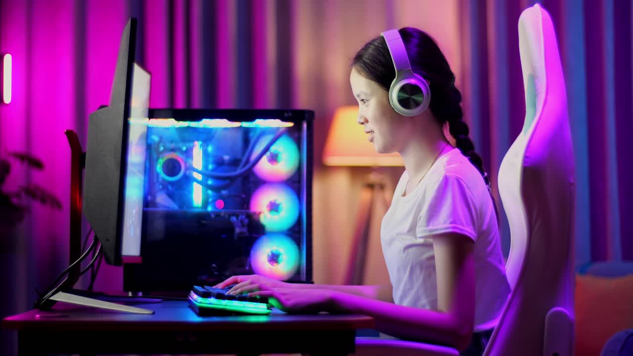 흥분한 아시아 십대 소녀 게이머는 컴퓨터에서 비디오 게임을 하면서 승리를 축하하고 춤을 춘다