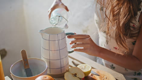 lady hands pouring water jug sitting fresh air closeup. woman at sunny terrace