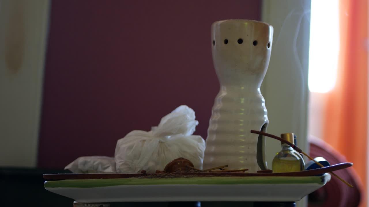 An incense stick is burning and releases a fragrant smoke inside the room.