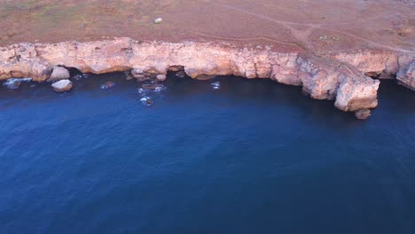 vista aérea de arriba hacia abajo de las olas salpicadas contra la costa rocosa, fondo