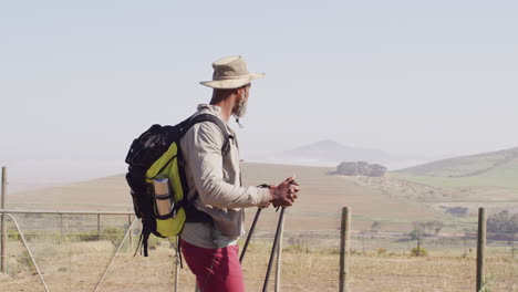 senior african american man hiking with trekking poles on sunny day, slow motion