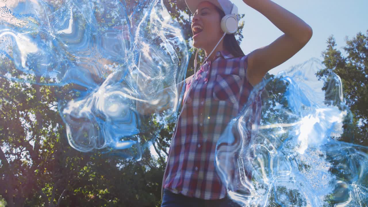 Woman holding headphones while singing to music in sunlit park, generating blue swirls around torso