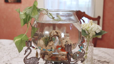 close up footage of an ornate fish bowl planter with goldfish swimming about in the bowl