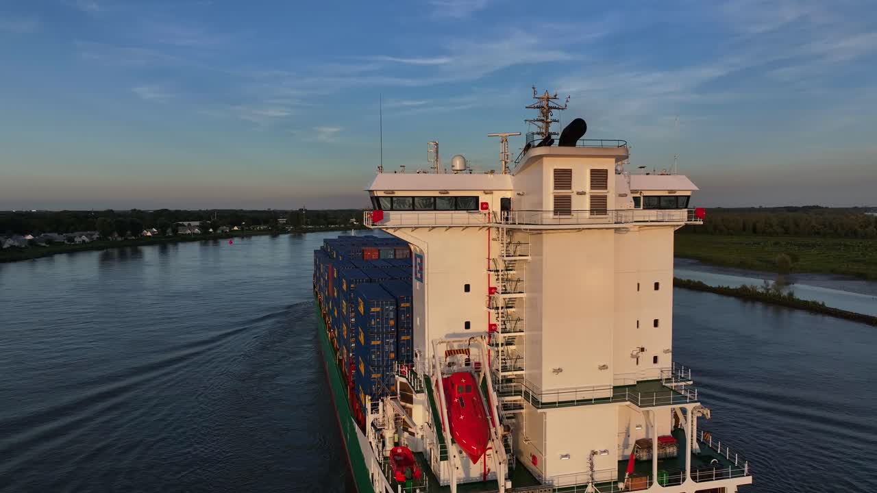 콘테이너 선박이 컨테이너를 쌓아 강을 따라 항해하는 모습, 해가 지면 찍힌 사진