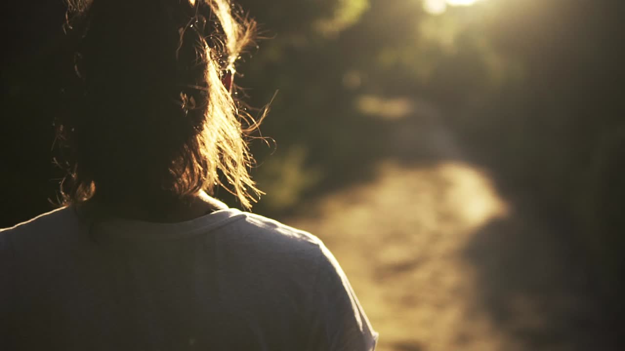 foto por encima del hombro de una modelo caminando por un sendero durante la puesta de sol