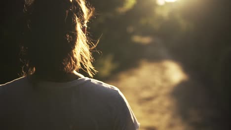 over-the-shoulder shot of a model walking along a path during sunset