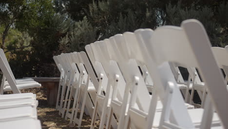 rows of white outdoor wedding chairs ready for romantic ceremony