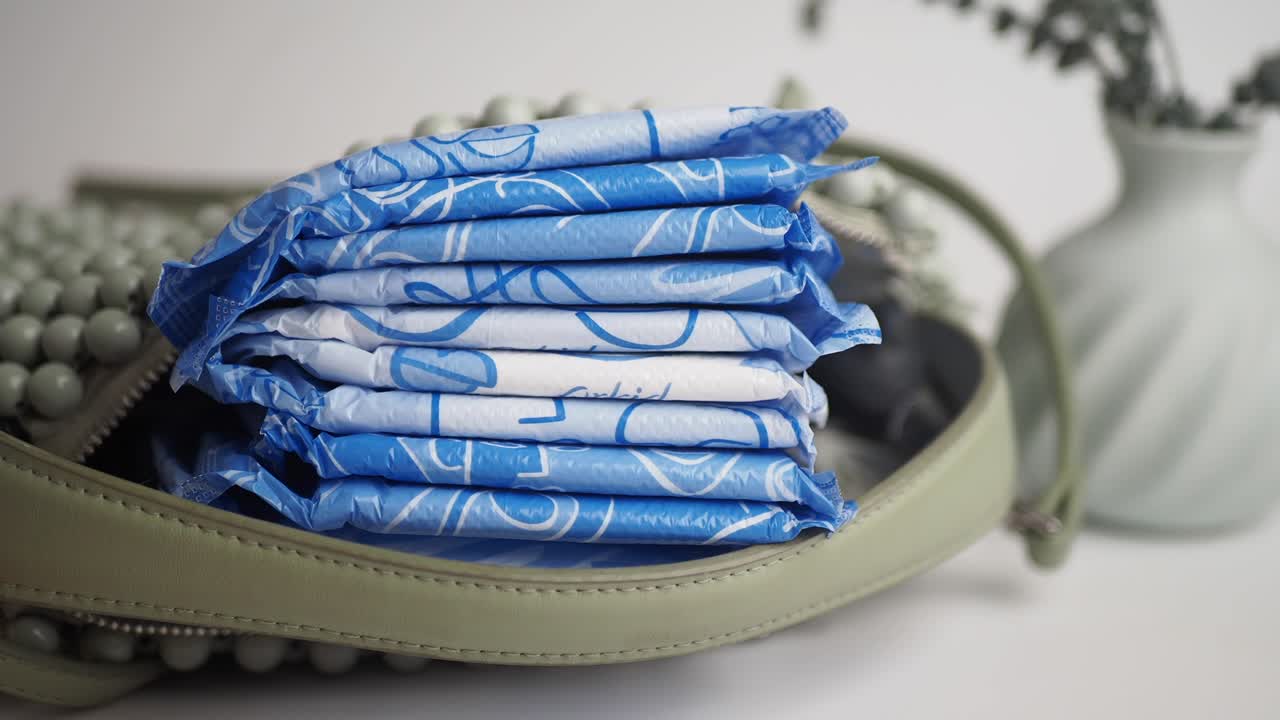 A stack of individually wrapped sanitary pads in a handbag