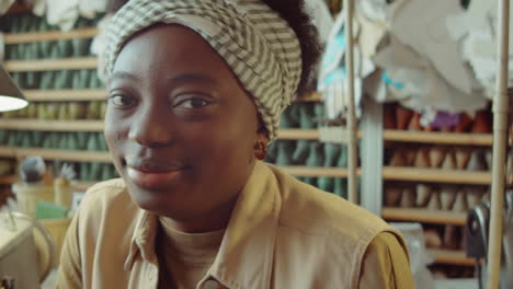 portrait of cheerful african american woman in shoemaking workshop